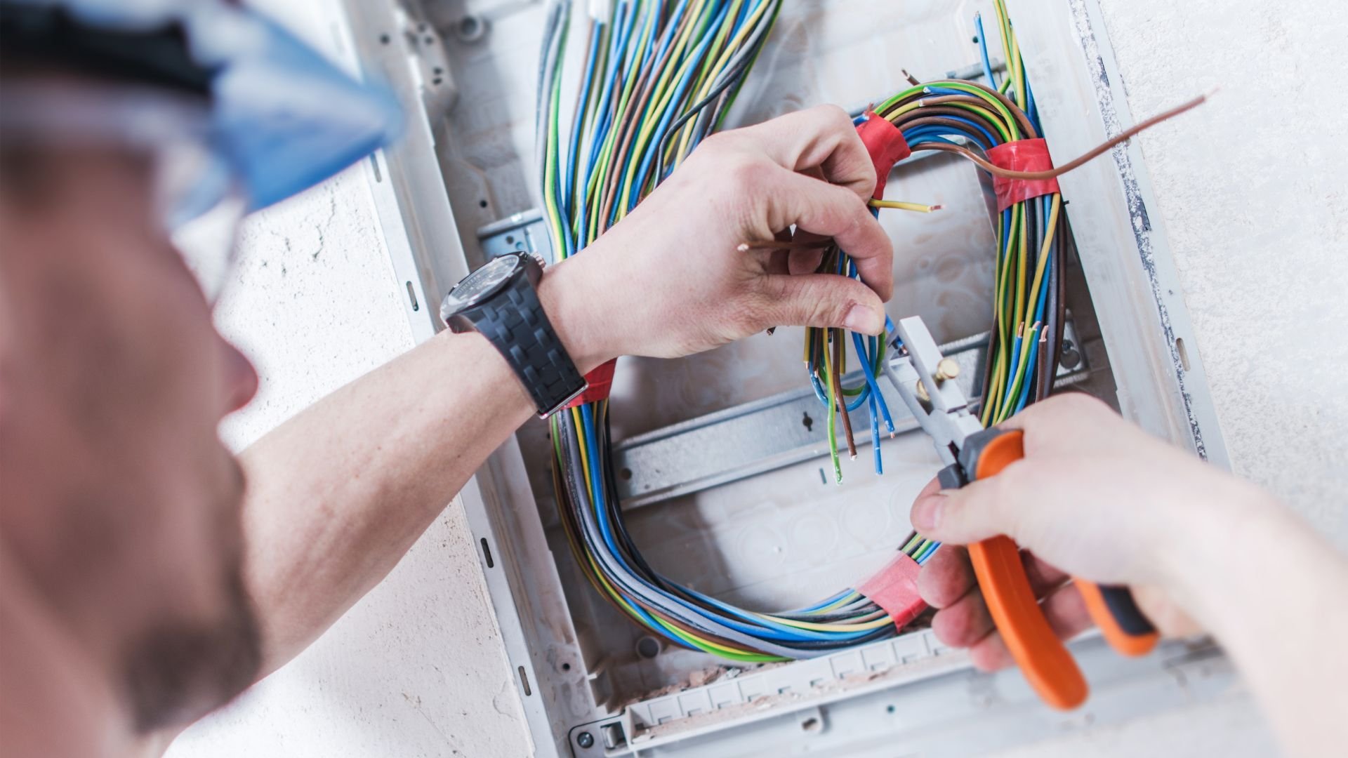 Electrician working on wiring with colored cables and pliers